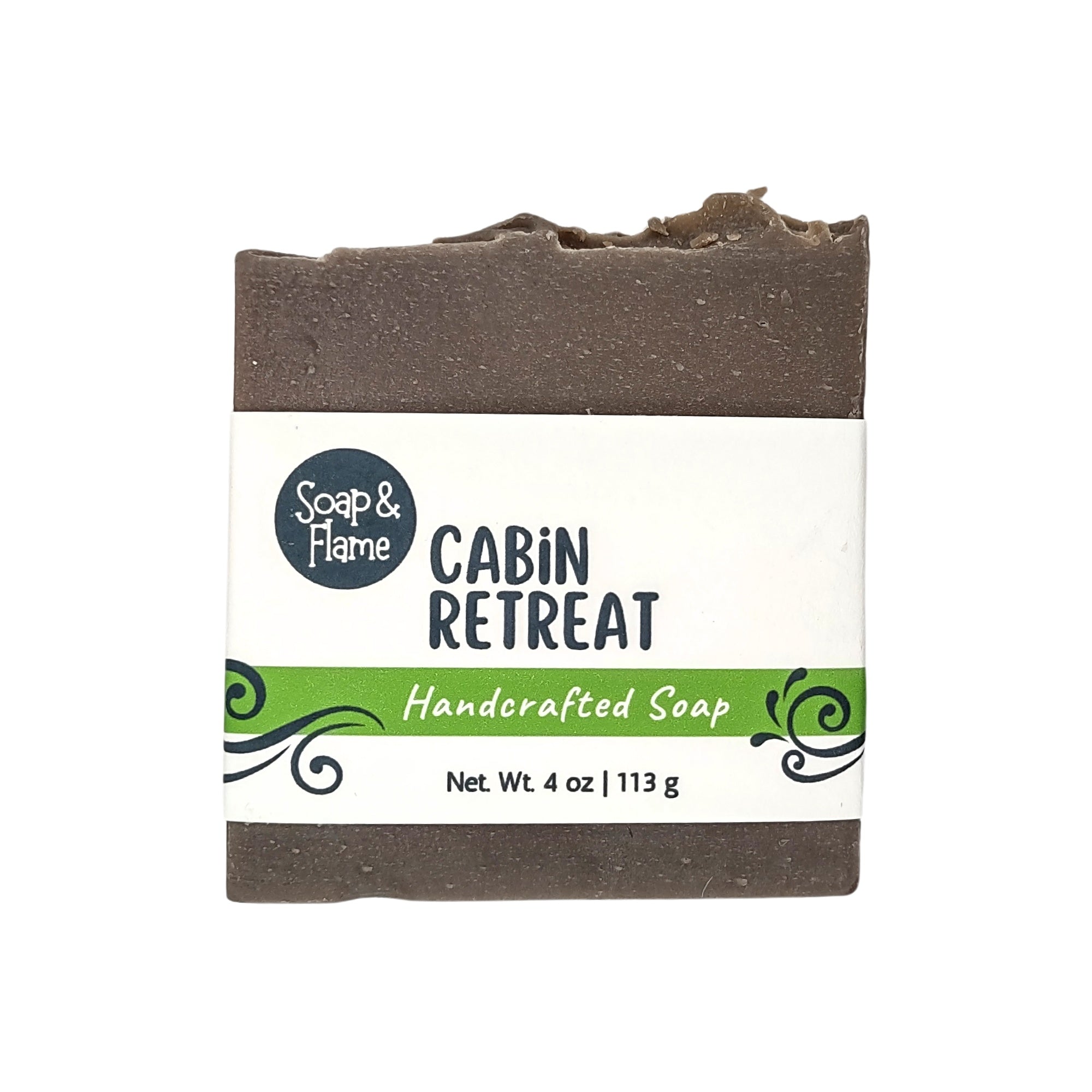 a soap named "Cabin Retreat" with a white background and a white band label with the brand Soap & Flame logo on it