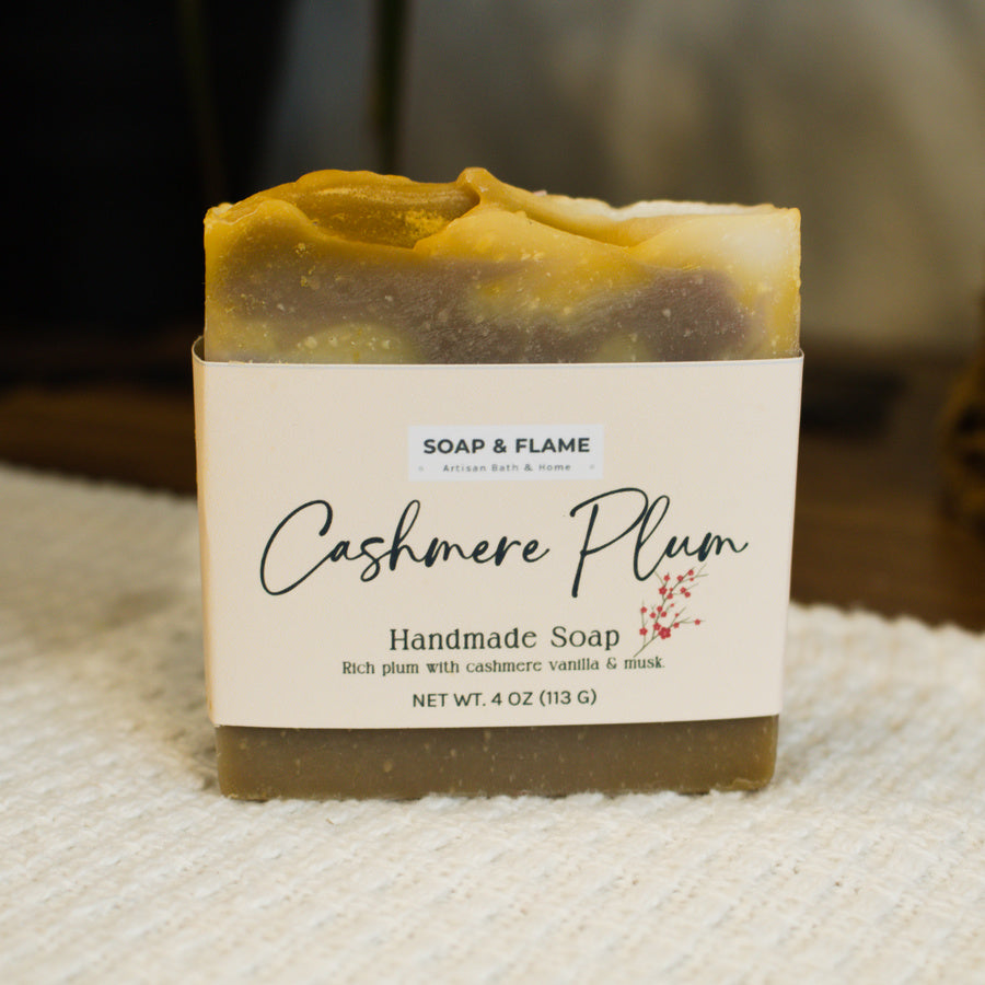Handmade soap bar with 'Cashmere Plum' label on a textured surface