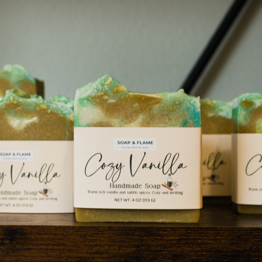 Handmade soap bars with 'Cozy Vanilla' label on a wooden surface