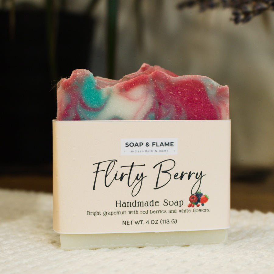 Handmade soap bar with 'Flirty Berry' label on a textured surface