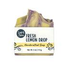 Handmade soap bar with a label indicating 'Fresh Lemon Drop' and 'Soap & Flame' brand on a white background with yellow strip.