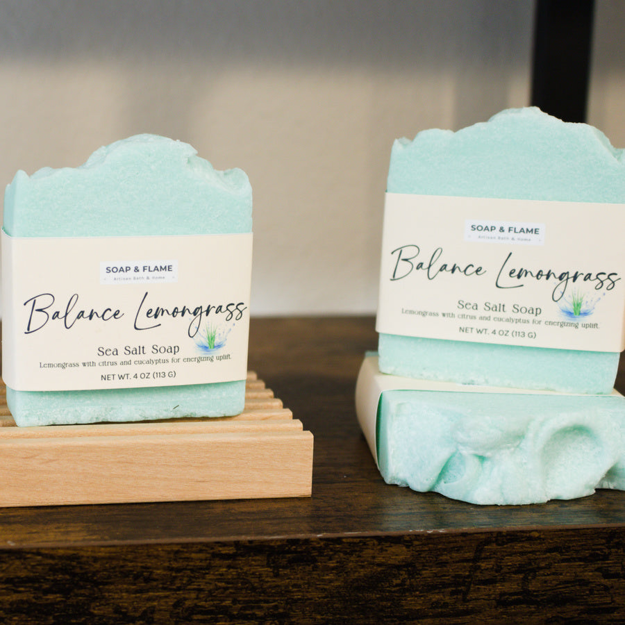 Two bars of Balance Lemongrass soap on a wooden stand with a blurred background