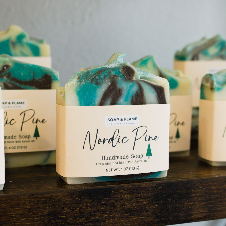 Handmade soap bars with 'Nordic Pine' label on a wooden surface