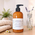 amber bottle of norwegian wildflowers hand and body lotion on a wood surface with a knit blanket folded next to it