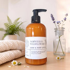 amber bottle of norwegian wildflowers hand and body lotion on a wood surface with a knit blanket folded next to it