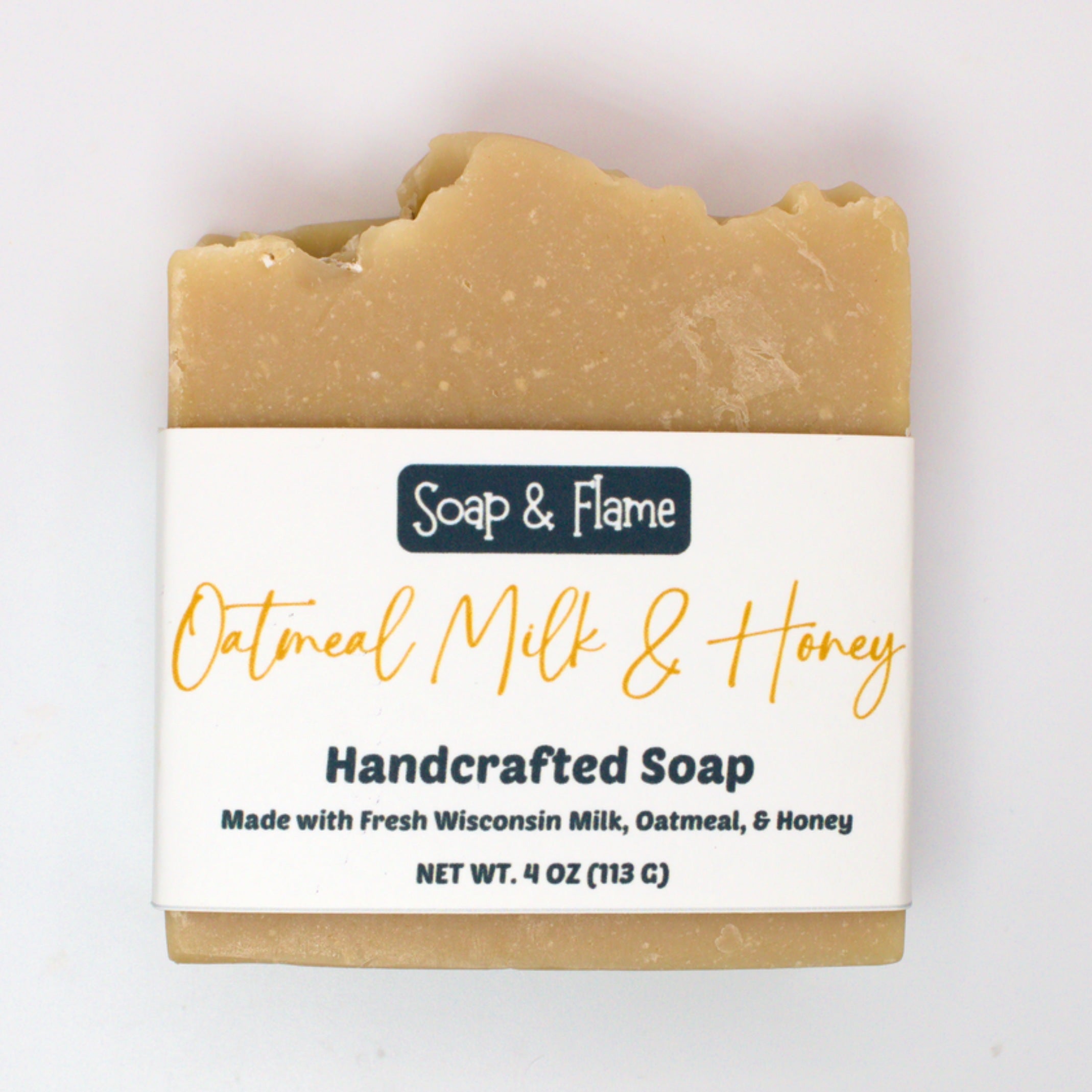 Handcrafted oatmeal milk and honey soap bar with 'Soap & Flame' label on a white background