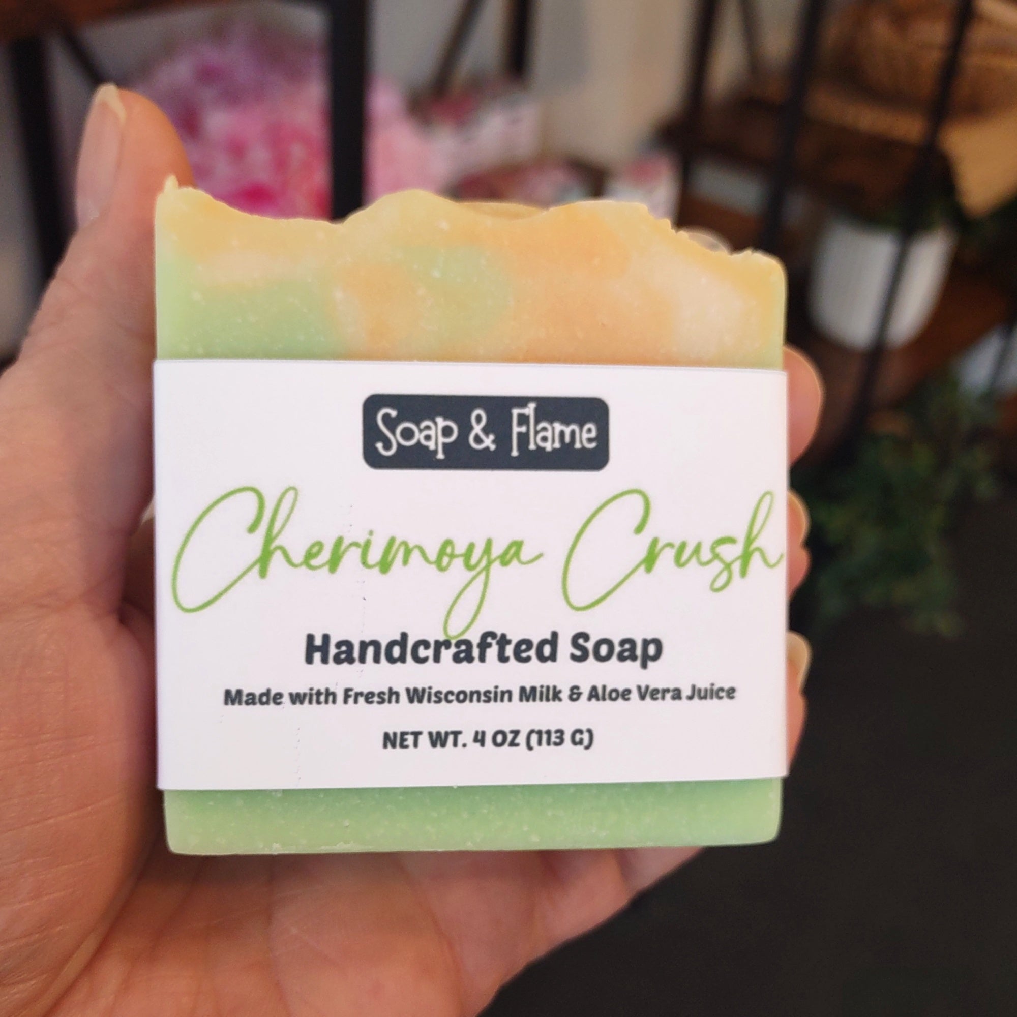Hand holding a bar of Soap & Flame Cherimoya Crush soap with a blurred background