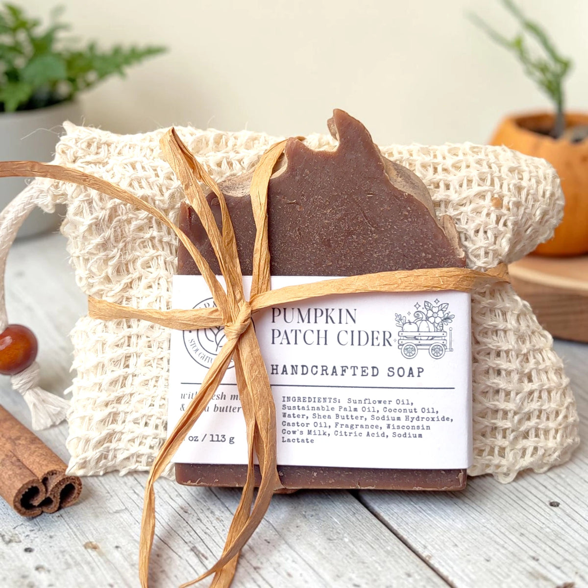 Pumpkin Patch Cider Essentials Gift Set: a soap bar tied with raffia in a natural sisal bag, styled with cinnamon sticks and a small pumpkin on a wood surface.