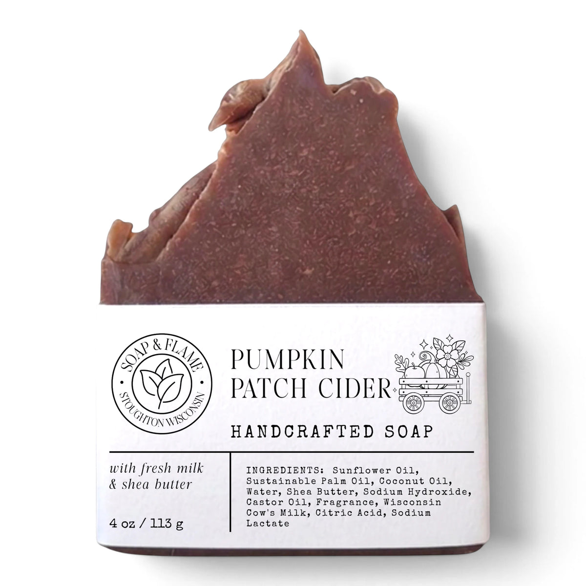 Close-up of a handmade pumpkin spice soap bar wrapped in a white paper label, showing the label text and rich brown soap texture.